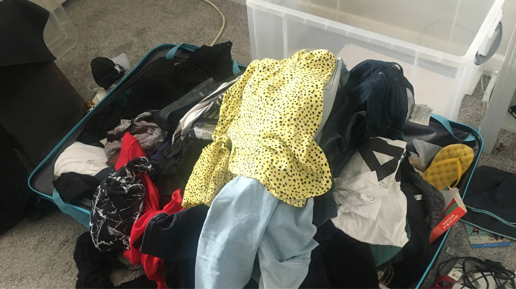 A messy suitcase full of clothes in a messy room